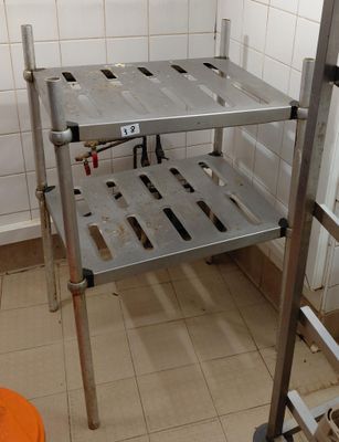 a metal shelf in the corner of a bathroom with a toilet