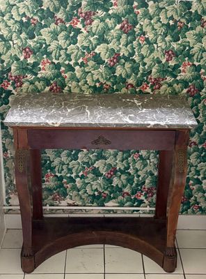 une petite table au plateau en marbre, placée devant un mur recouvert de papier peint