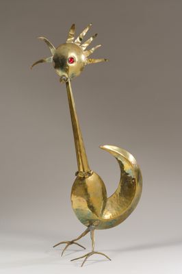 une sculpture en or représentant un oiseau avec un œil rouge sur la tête