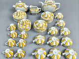 yellow and white porcelain tea set with matching cups and saucers