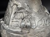 a silver vase that has a picture of a man on a horse