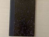 un cahier noir à la couverture bleue posé sur une table blanche