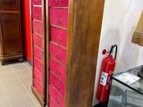 une grande armoire en bois aux tiroirs roses dans une pièce