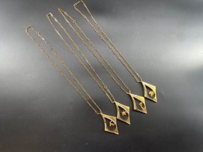 un ensemble de quatre colliers en or posés sur un fond noir