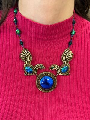 un gros plan sur une femme portant un pull rouge et un collier bleu