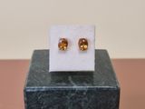 a close up of a pair of earrings on top of a marble block