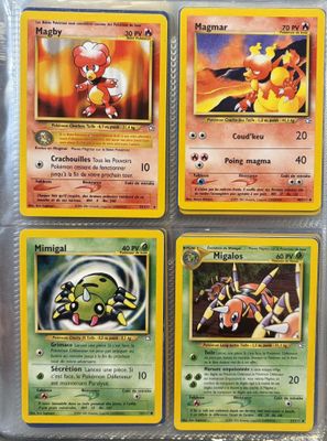 Quatre cartes Pokémon se trouvent dans un étui en plastique posé sur une table.