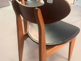 a wooden chair with a black seat in a room