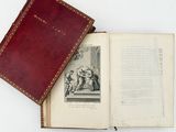 an open book with a red cover sitting on top of a white table