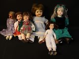 five dolls sitting next to each other on a black surface