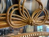 a mirror with a gold frame and a bow on top of it
