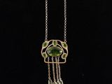 a gold and green necklace with a bird design on it