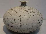 a white vase with brown spots on it on a table