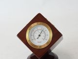 a small wooden clock on a stand on a white surface