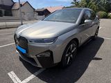 a silver bmw suv parked in a parking lot with houses in the background
