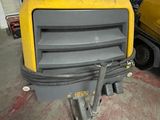 a yellow and black machine in a garage with a yellow truck in the background
