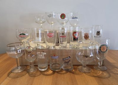 bottles and glasses are lined up on a table in front of a white wall