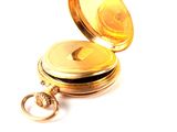 a gold pocket watch sitting on a white surface
