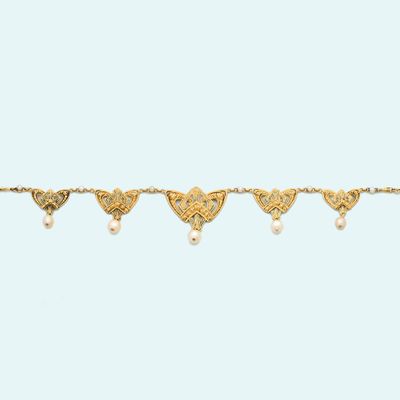 a close up of a gold bracelet with hearts and pearls