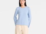 une photo d'une femme portant un pull bleu clair et un pantalon beige