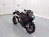 une moto noire garée dans une pièce aux murs blancs