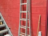 une échelle appuyée contre un mur rouge, à côté d'un escalier