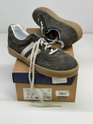 une paire de baskets grises avec des lacets blancs posée sur une boîte