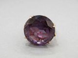 a close up of a purple stone ring on a white surface