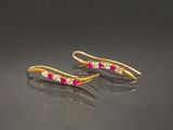 une paire de boucles d'oreilles en rubis et diamants sur un fond noir