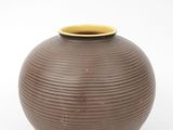 a brown vase with a yellow rim sitting on a white surface
