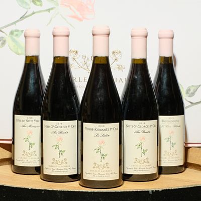 four bottles of wine are lined up on a wooden tray