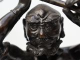 bronze statue of a man holding a hammer over his head