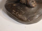 a bronze statue of a dog sitting on top of a rock