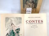 un livre ouvert posé sur une table blanche à côté d'un livre