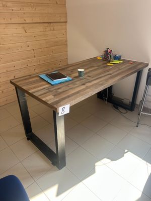 une table en bois sur laquelle est posé un ordinateur portable, dans une pièce