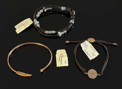 trois bracelets et une pièce de monnaie sont posés sur une surface noire