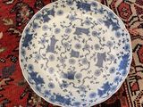 two blue and white plates sitting on a red rug
