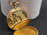 a gold pocket watch sitting on a black surface