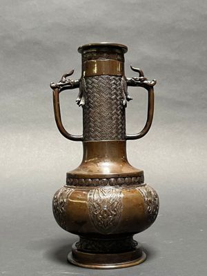 a bronze vase with two birds on the handle