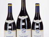 three bottles of wine are lined up on a white surface
