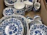 une boîte remplie d'assiettes et de bols bleus et blancs