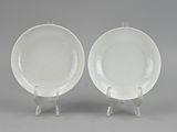 pair of white porcelain plates on stand on grey background