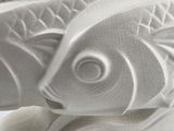 a white sculpture of a fish on a white surface