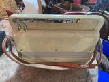 someone is holding a tan purse with a handle and a strap