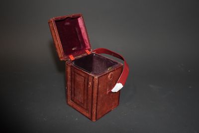 une petite boîte en bois avec une poignée rouge sur un fond noir