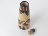 a small vase with a picture on it next to a cork stopper