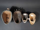 several wooden masks are lined up against a black wall