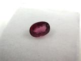 a red oval ruby stone on a white surface