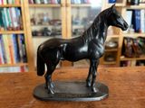 une statue de cheval posée sur une table devant une bibliothèque