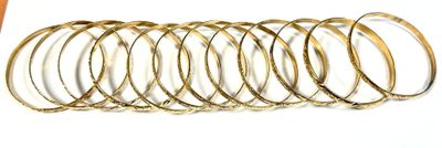 a stack of gold bangles on a white surface